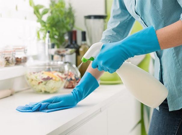 person cleaning a counter with a spray cleaner and rag