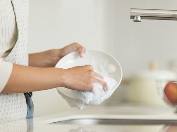 person washing a plate at the sink